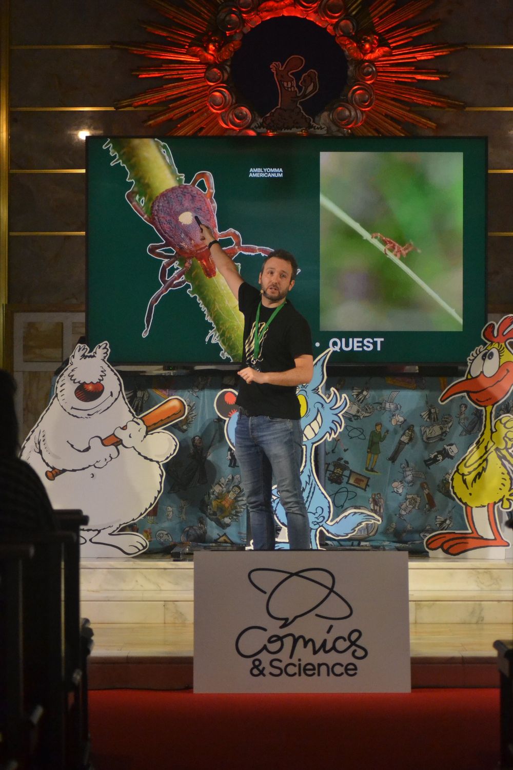 Andrea sul palco di Comics&Science davanti a uno schermo con la foto di una zecca