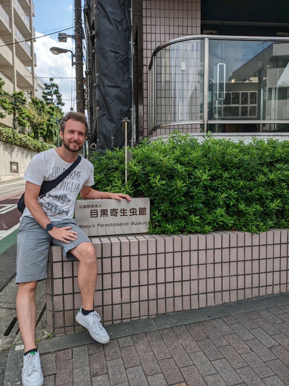 Andrea seduto accanto all'insegna del Meguro Parasitological Museum di Tokyo