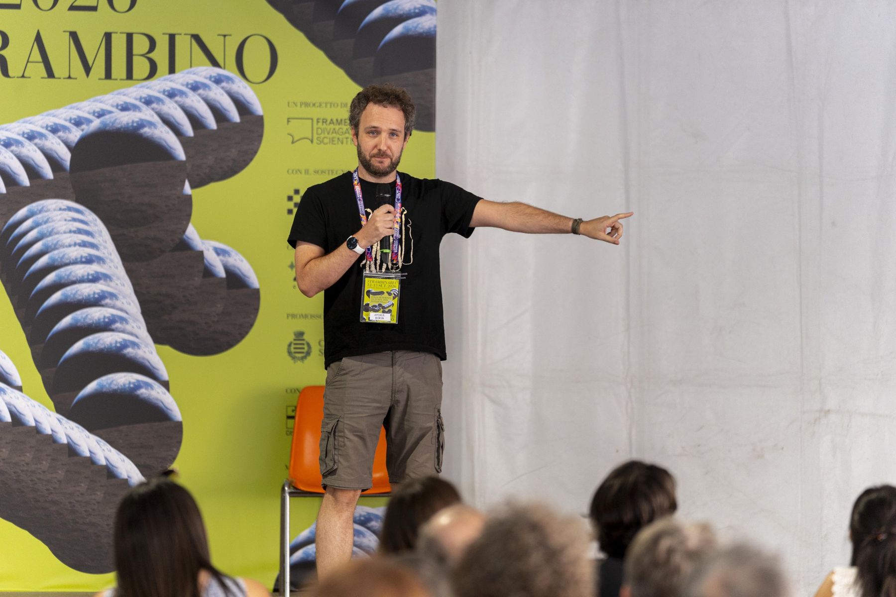 Andrea sul palco mentre parla al pubblico, con un microfono in mano